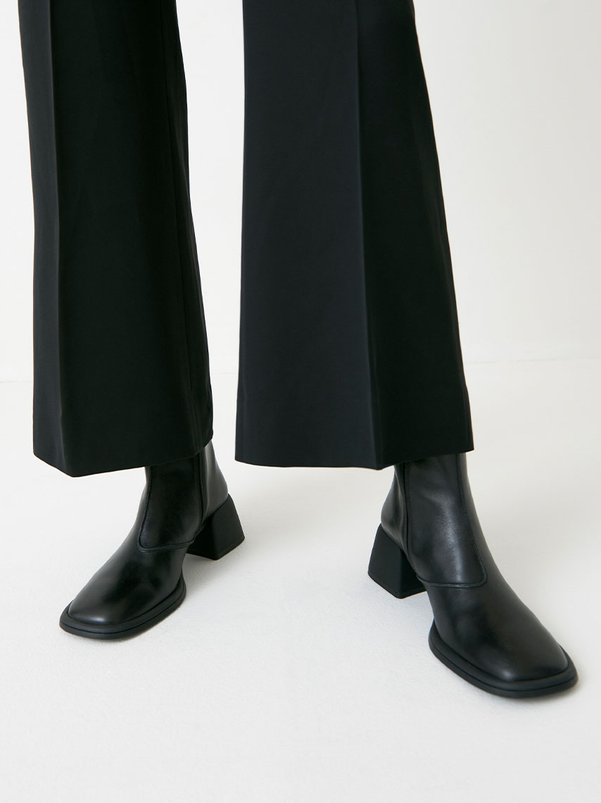 Ansie boots med fyrkantig tå-form i svart skinn, är stylade med en off-white midi-kjol.