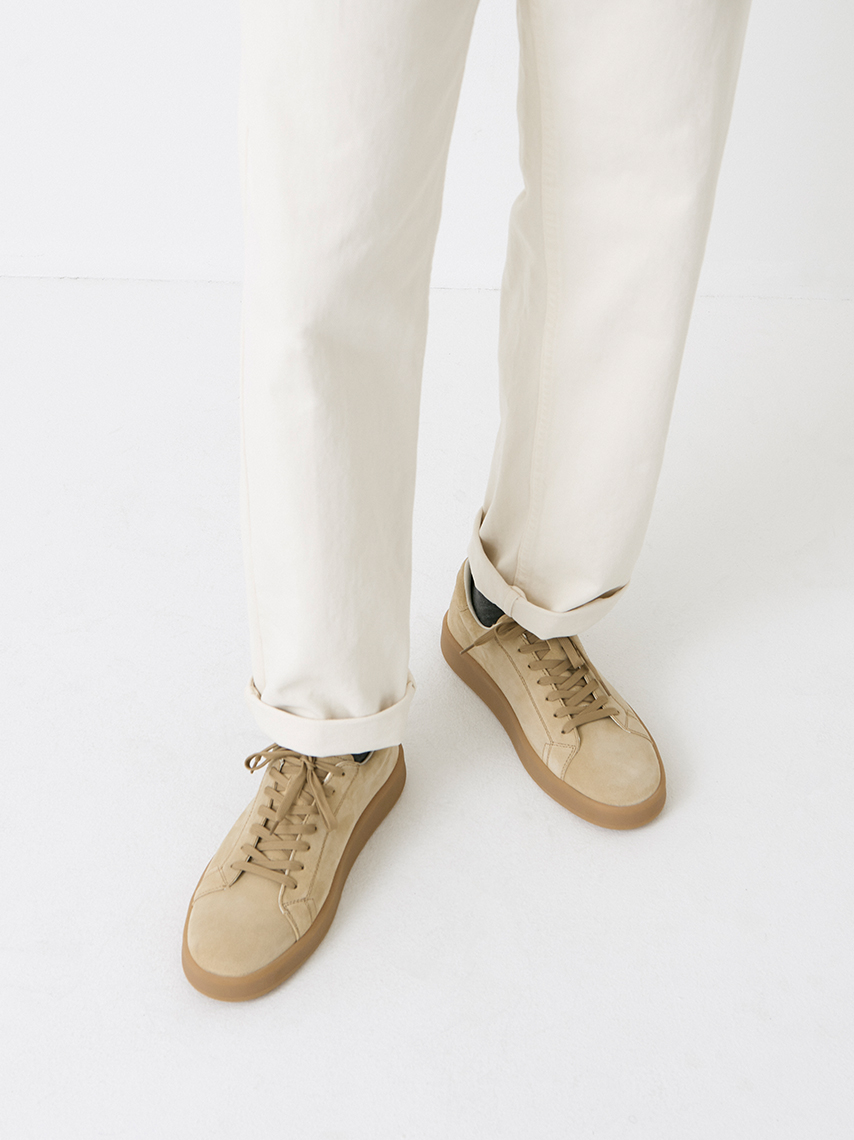 Low-cut sneakers Leo in beige suede with honey-colored outsoles, styled with white jeans.