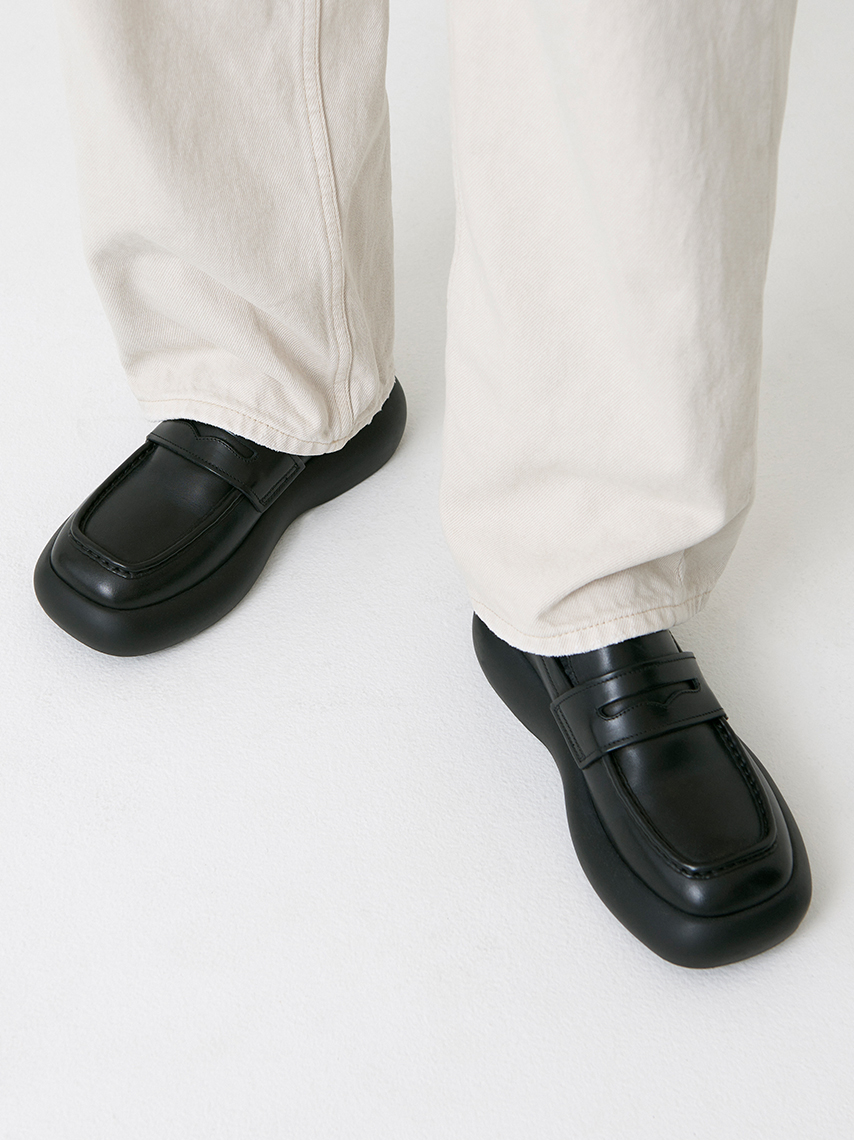 Black Janick loafers with rounded, chunky outsoles, styled with white, wide jeans.