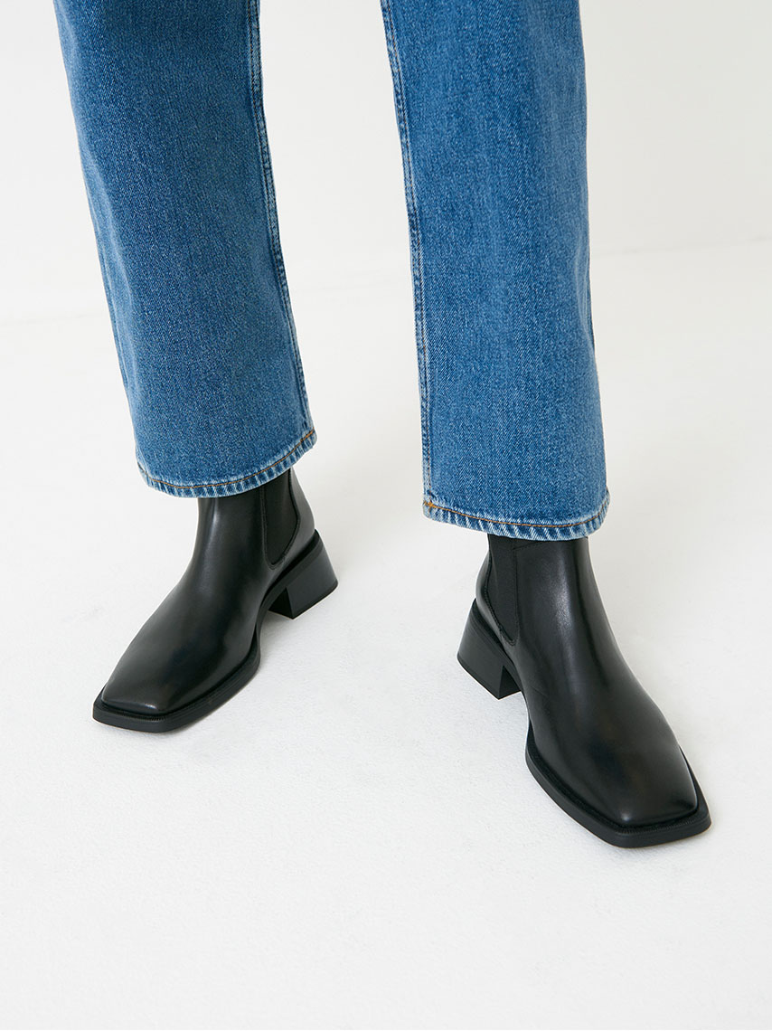 Detailjvy av stretch-bootsen Blanca i svart, med skarp, fyrkantig tå-form och medelhöga blockklackar.