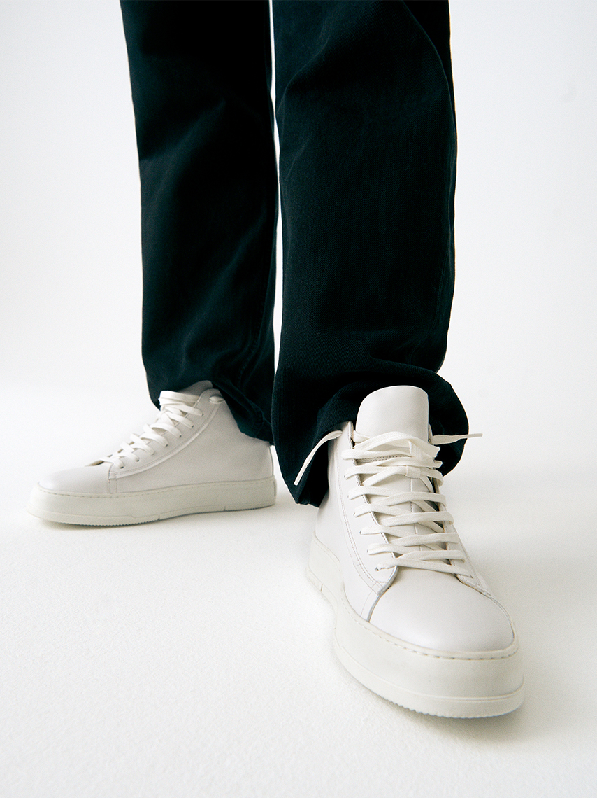 The John sneakers in all white leather with chunky sole styled with black costume pants