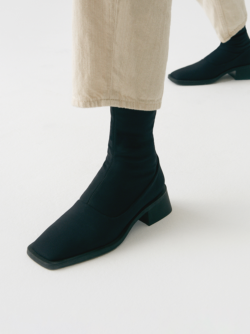 Detail view of stretch boots Blanca in black, with sharp square-toe shape, and medium-high block heels.