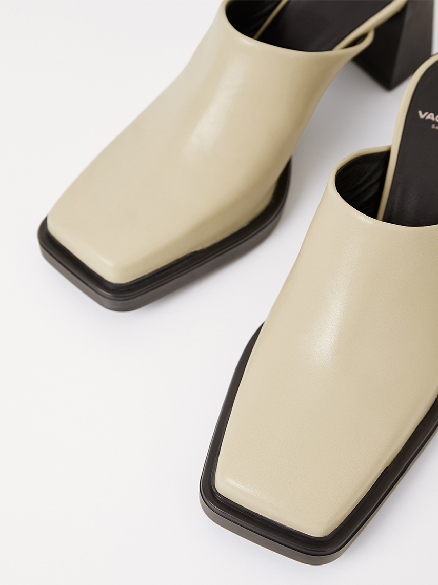 The Edwina-mules in off-white leather with slip-in design, square toe and black soles