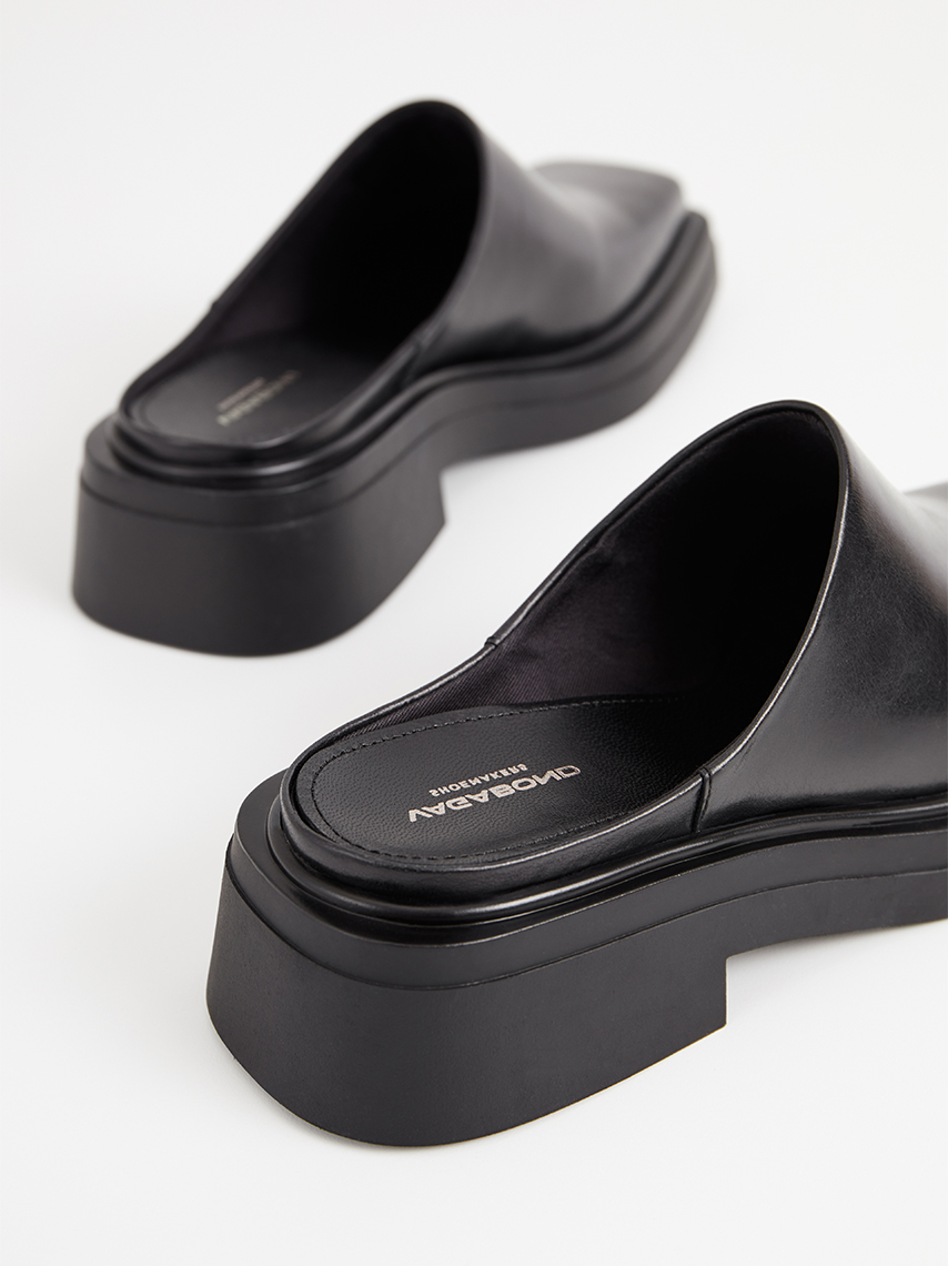 The Eyra mules in black leather with slip-in design, square toe and black soles