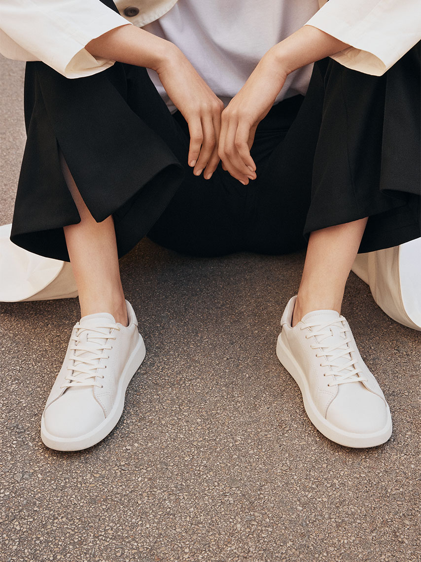 Detail view of all-white Maya low-top sneakers in leather, with thin outsoles. 